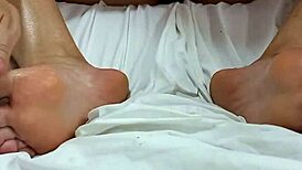 BRUNETTE APPLYING OIL TO HER FEET WITH RED NAILS