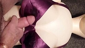Dolly gives handjob in bra, ending with cumshot.