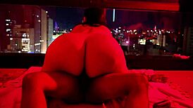 Brunette chubby girl sits on big dick under red light, contrasting her small tits with the intense action.