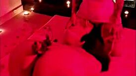 Brunette chubby girl sits on big dick under red light, contrasting her small tits with the intense action.