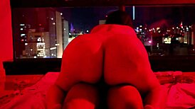 Brunette chubby girl sits on big dick under red light, contrasting her small tits with the intense action.