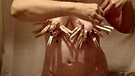 slave performs auto-session with clamps, belt, and dildo outdoors