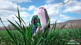 Goddess displays cute curly toes in white socks beneath jeans on spring grass field