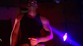 muscular bodybuilder strokes massive cock in purple orange shadows